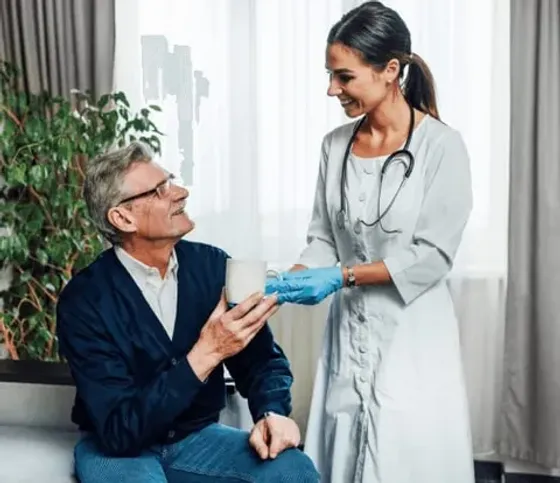 Nurse handing a cup to a seated patient during a consultation